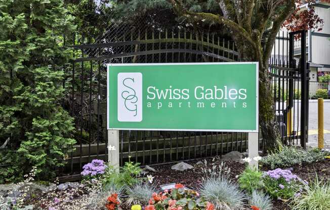 Swiss Gables Property Sign with Multicolor Flowers Underneath it at Swiss Gables Apartment Homes, Kent