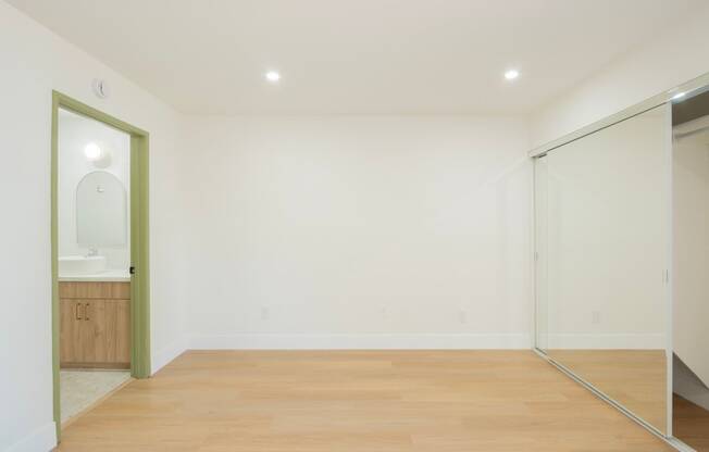 a living room with white walls and a sliding glass door to a bathroom