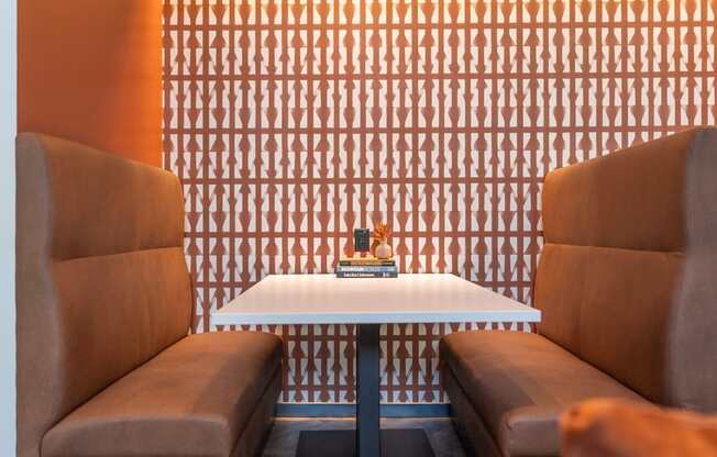 Two brown chairs are facing a white table with a book on it.