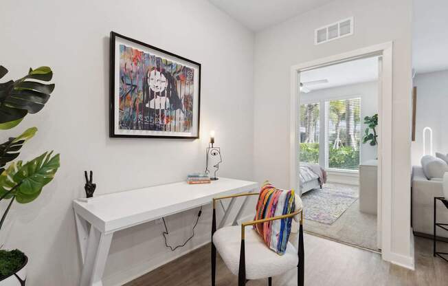 A room with a white desk and a chair with a colorful throw pillow.