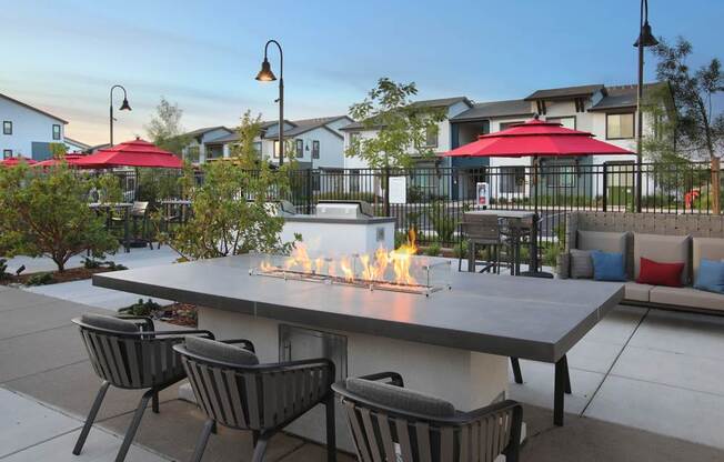 A patio with a fire pit and chairs.