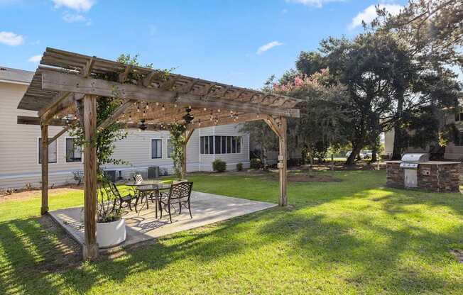 A wooden pergola with a table and chairs under it.
