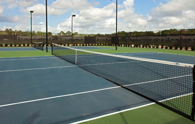 A tennis court with a net and two light poles.
