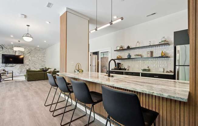 A kitchen with a marble countertop and black chairs.