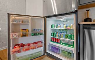 A refrigerator is open, showing a variety of food items on the shelves.