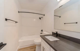 Model Bathroom with White Cabinets and Wood-Style Flooring at Palmilla Apartments located in San Diego, CA.