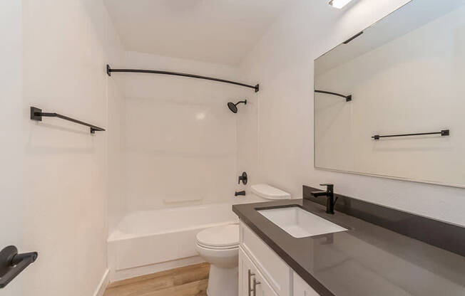 Model Bathroom with White Cabinets and Wood-Style Flooring at Palmilla Apartments located in San Diego, CA.