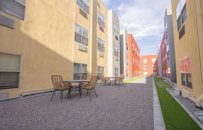 a courtyard with tables and chairs in a row of apartment buildings