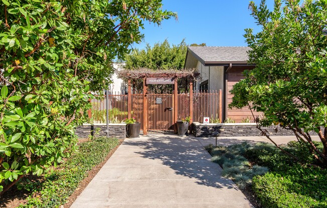 A small building with a brown fence and gate is surrounded by green bushes.