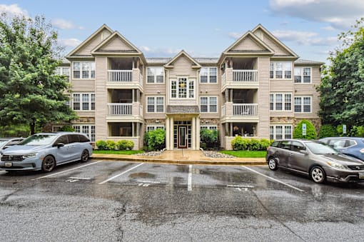 A large apartment complex with a parking lot in front.