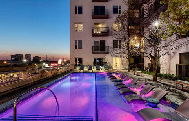 A pool with purple lighting on the side of a building.