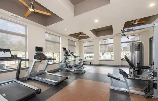 A spacious gym with treadmills, elliptical machines, and a weight rack.