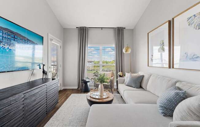 A modern living room with a large flat screen TV mounted on the wall.