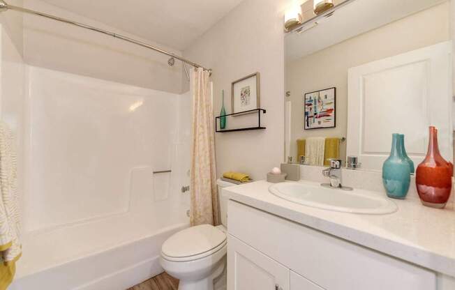 A white bathroom with a toilet, sink, and shower.
