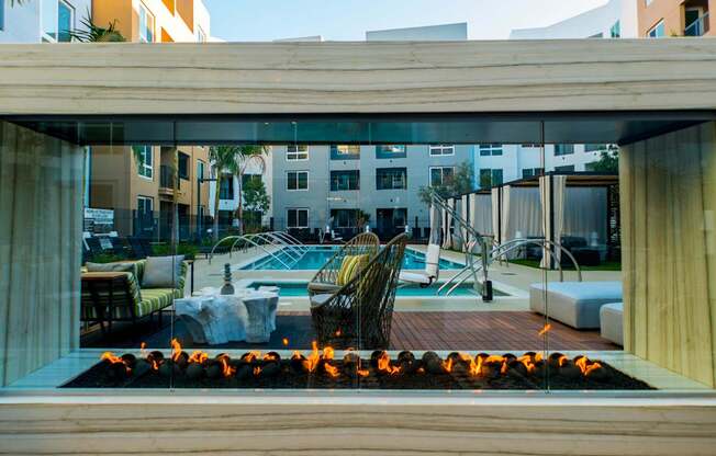 A modern outdoor pool area with a fire pit in the foreground.