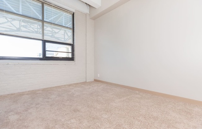 an empty living room with a window and white walls