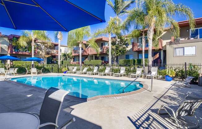 a resort style swimming pool with chaise lounge chairs and umbrellas