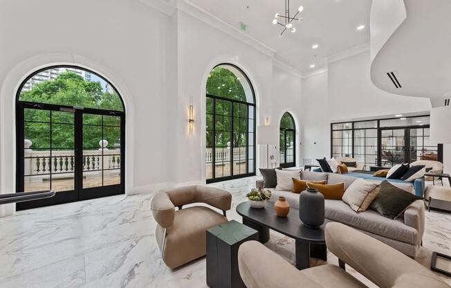 Comfy beige chairs with black coffee tables against a marble floor.