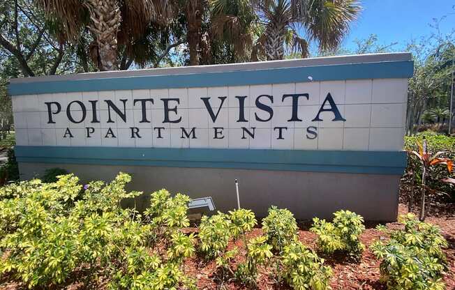 Property Sign with landscaping shrubbery underneath it and trees in the back ground