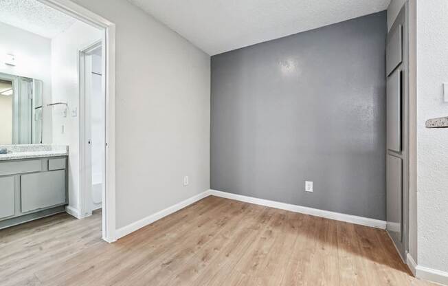 A room with a wooden floor and a grey wall.