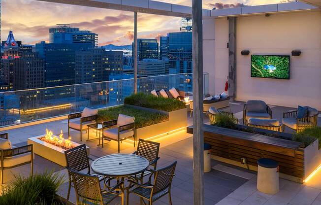 A rooftop patio with a table, chairs, and a TV.