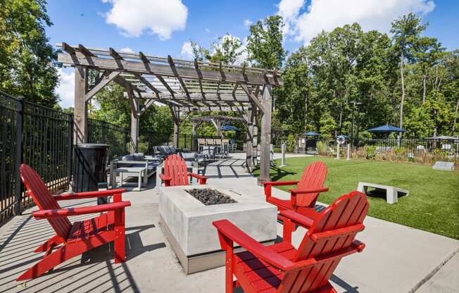 an outdoor patio with red chairs and a firepit