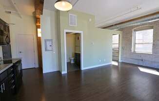 an empty living room with wood floors and a brick wall