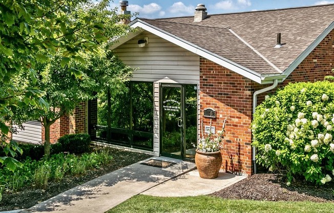 a walkway in front of a brick house with a patio and a glass door