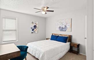 A bedroom with a bed, chair, and painting on the wall.