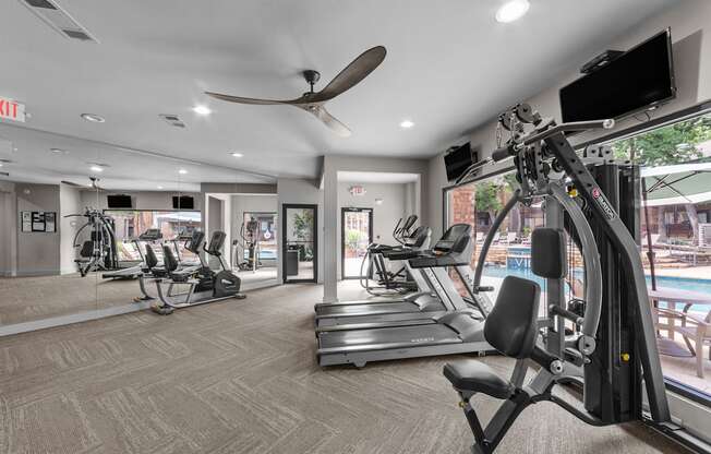 A gym with a variety of equipment including treadmills, weights, and a television.