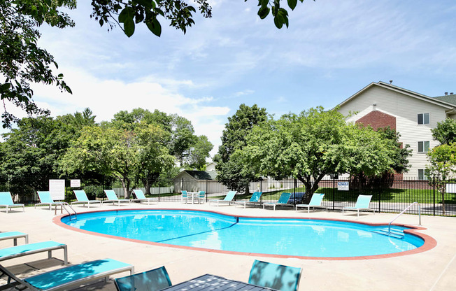 A pool surrounded by trees and chairs.