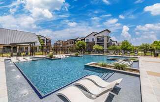 a swimming pool with lounge chairs and buildings in the background