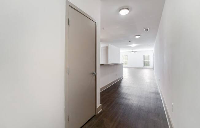 an empty living room and kitchen with white walls and wood flooring