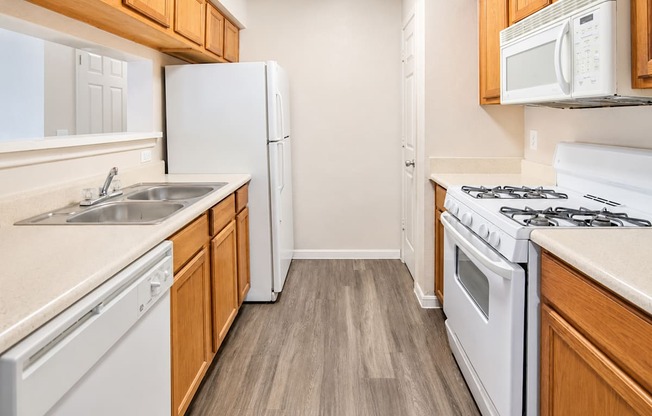 A kitchen with white appliances and wooden cabinets.