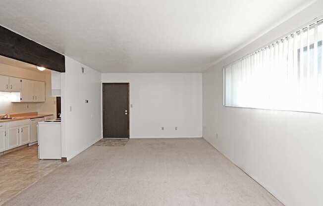 A room with a brown door and a window with white curtains.
