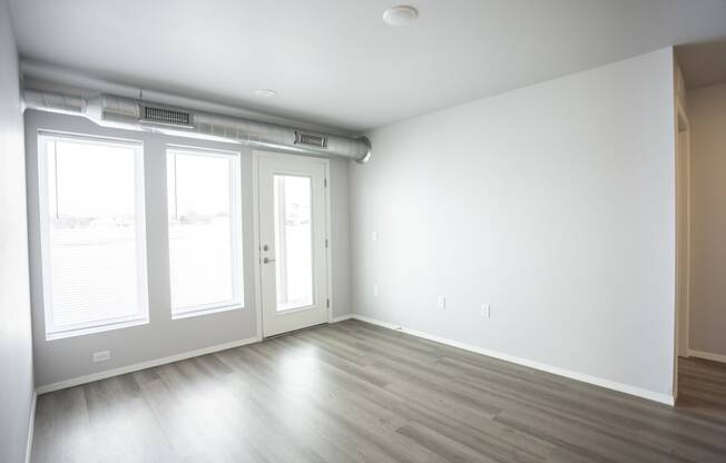 Empty living room with large, bright windows.