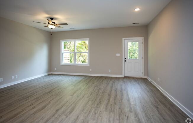 an empty living room with wood floors and a ceiling fan