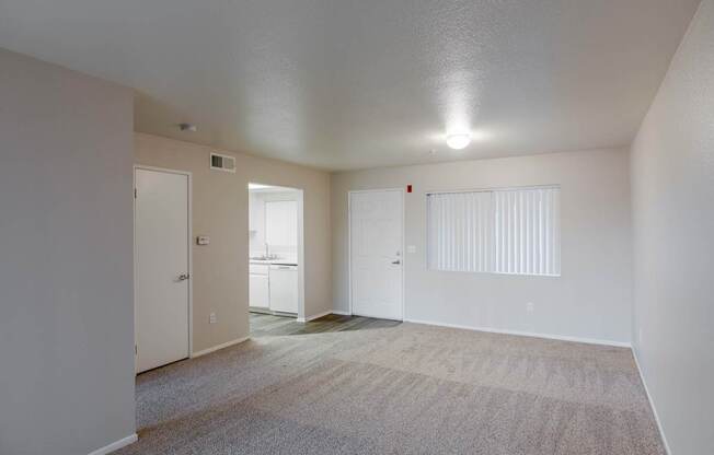 the living room of an apartment with carpet and a door to the bathroom