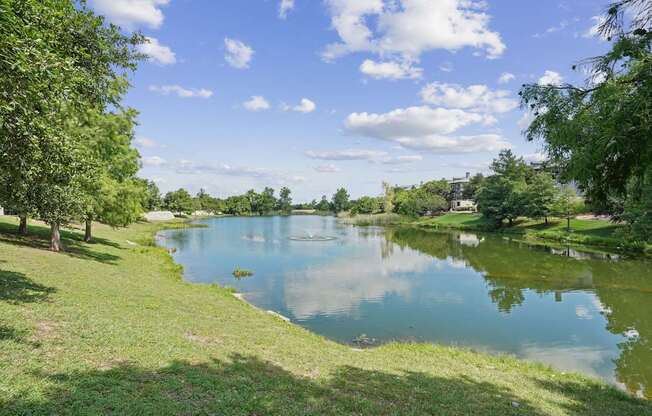 A serene lake surrounded by lush greenery under a clear blue sky.