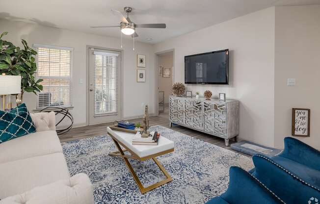 A living room with a white couch, a blue couch, a coffee table, and a television.