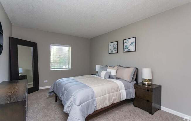A bedroom with a bed, nightstand, and two pictures on the wall.