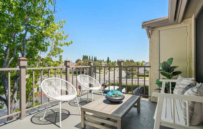 a patio with two chairs and a table on a balcony