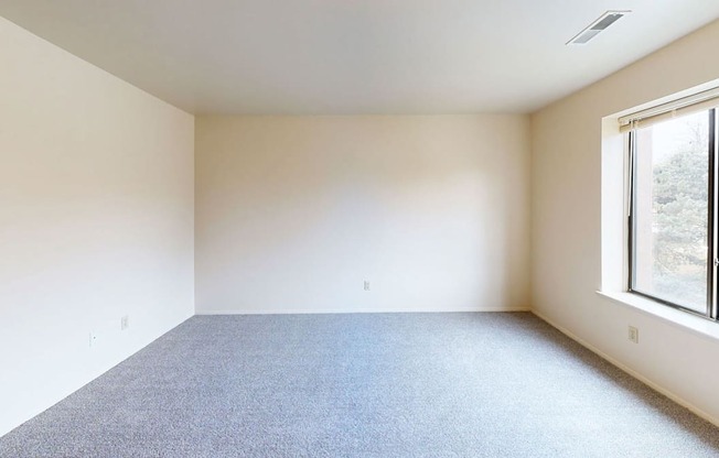 spacious bedroom with a large window and carpet