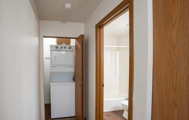 a hallway with a door to a room with a washer and dryer and a laundry room with a. Fargo, ND Westview Towers Apartments