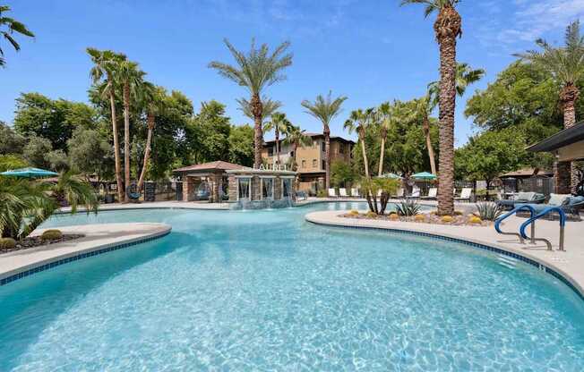 A large swimming pool surrounded by palm trees and lounge chairs. at The Laurel Apartments, Chandler