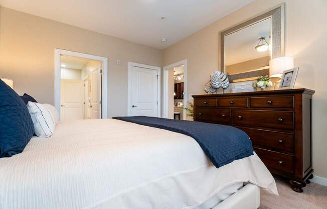 A bedroom with a large bed and a dresser with a mirror above it.