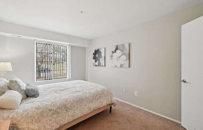 A bedroom with a bed, a lamp, and two pictures on the wall.