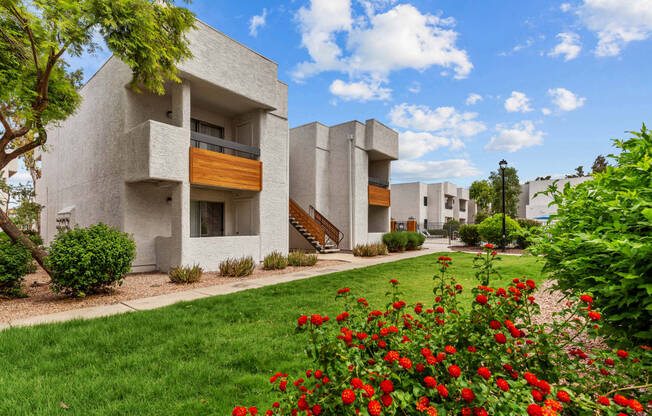 a building with a green lawn and red flowers in front of it