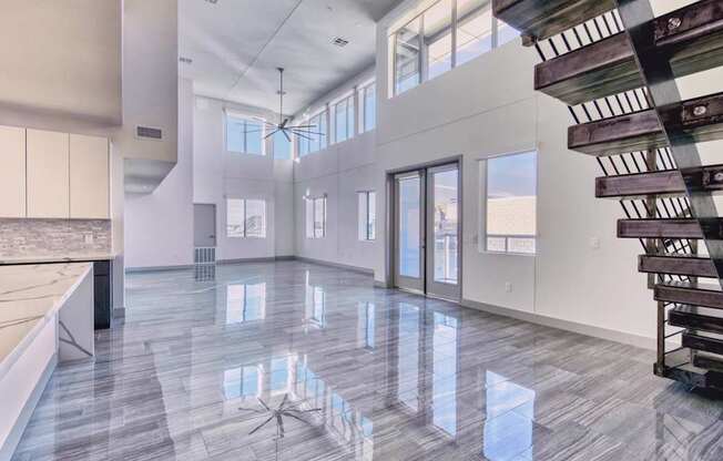 A spacious interior with a marble floor and a staircase on the right.