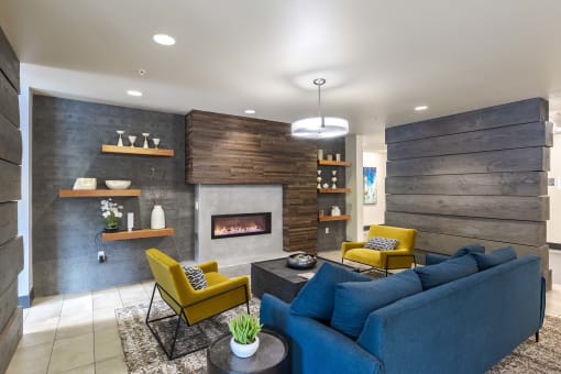 a living room with a blue couch and yellow chairs and a fireplace